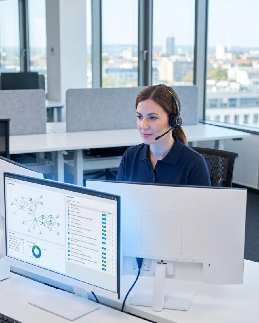Help desk technician monitoring network dashboards at a multi-screen workstation